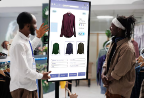 Deux personnes utilisant une borne tactile dans un magasin de vêtements.